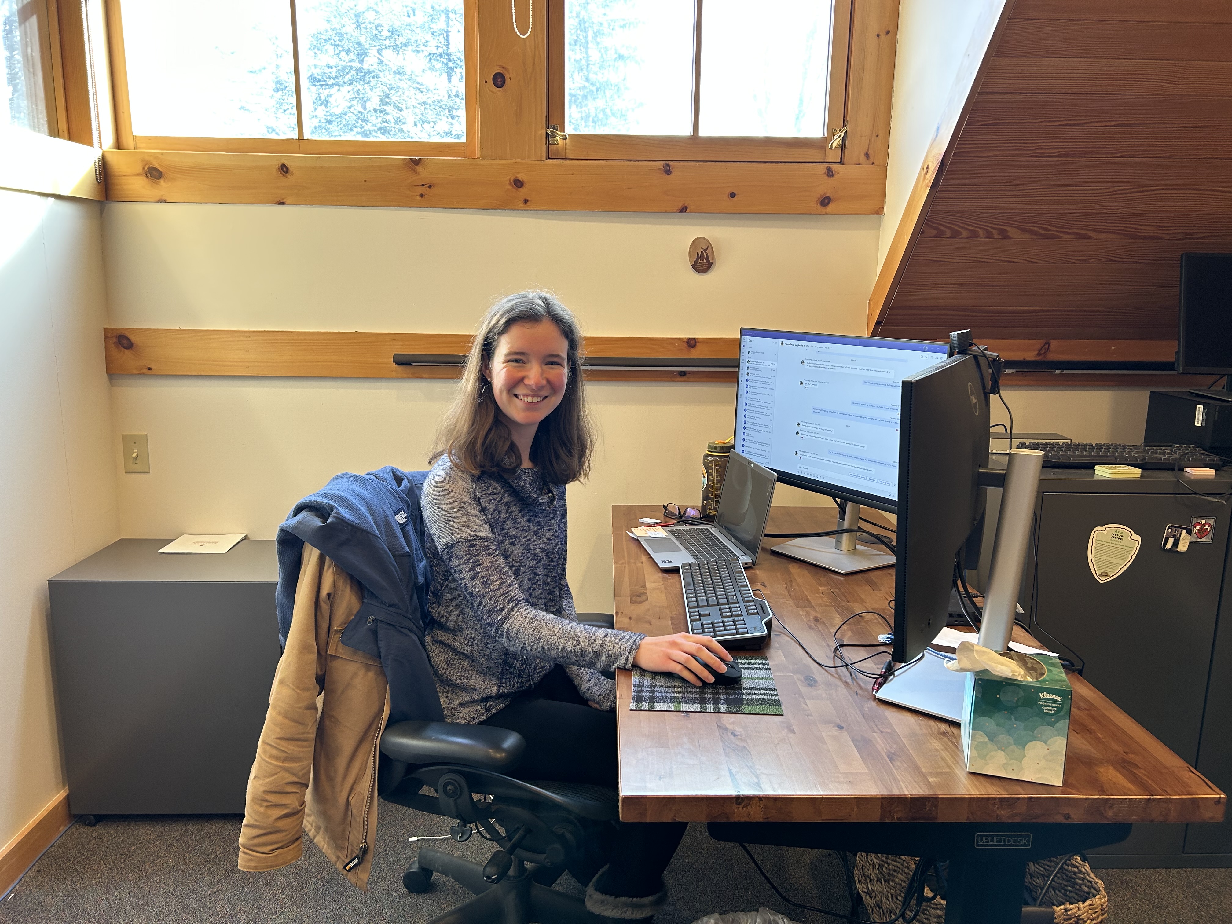 A woman smiles while sitting at a desk
